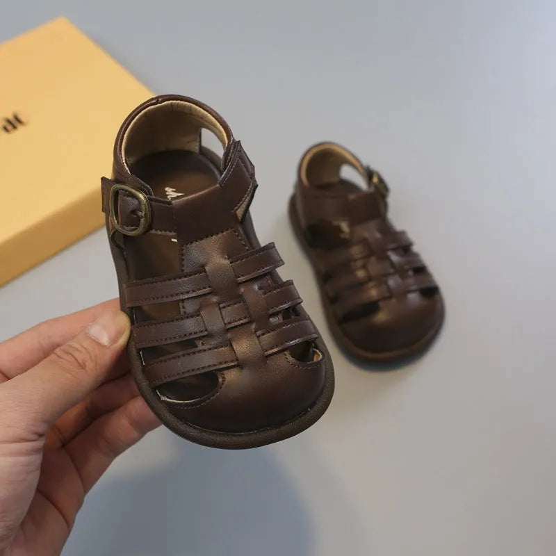 Girls' closed toe PU leather woven hollowed Roman sandals with Velcro strap, beige colour, on toddler feet