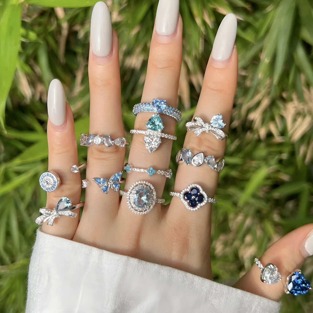 Women's S925 sterling silver ring with sea blue zircon heart or bow shape on plain background