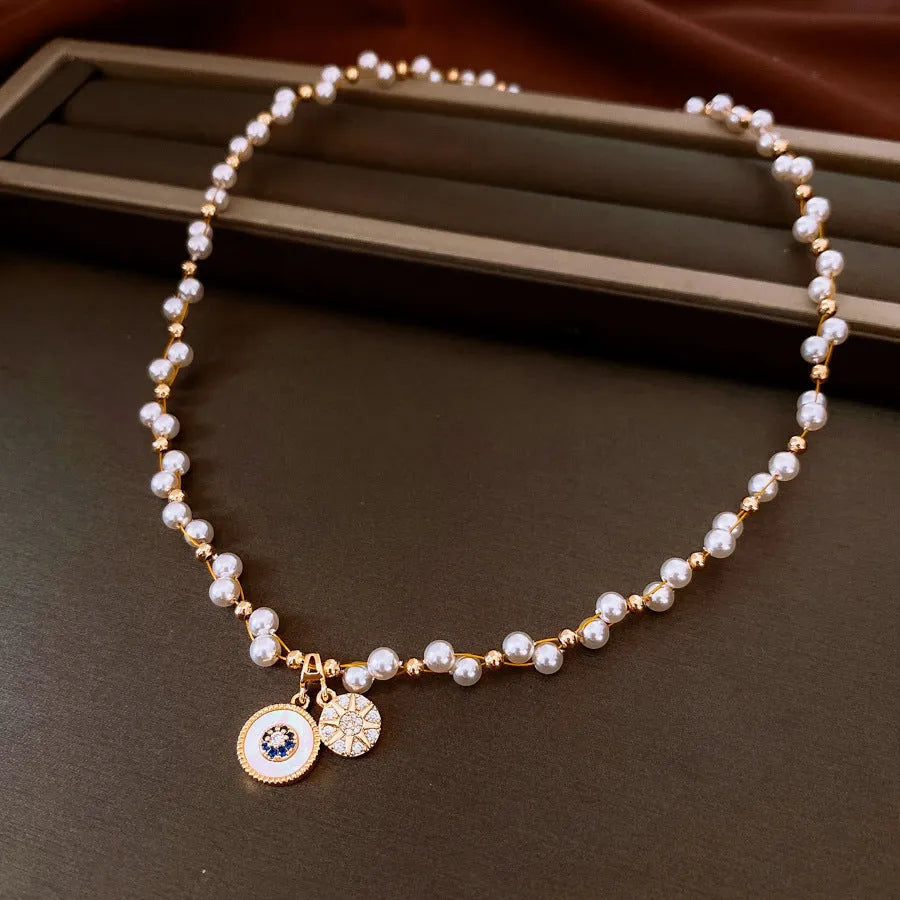 Gold-white electroplated necklace with round imitation pearl and zircon pendant on an adjustable clavicle chain.