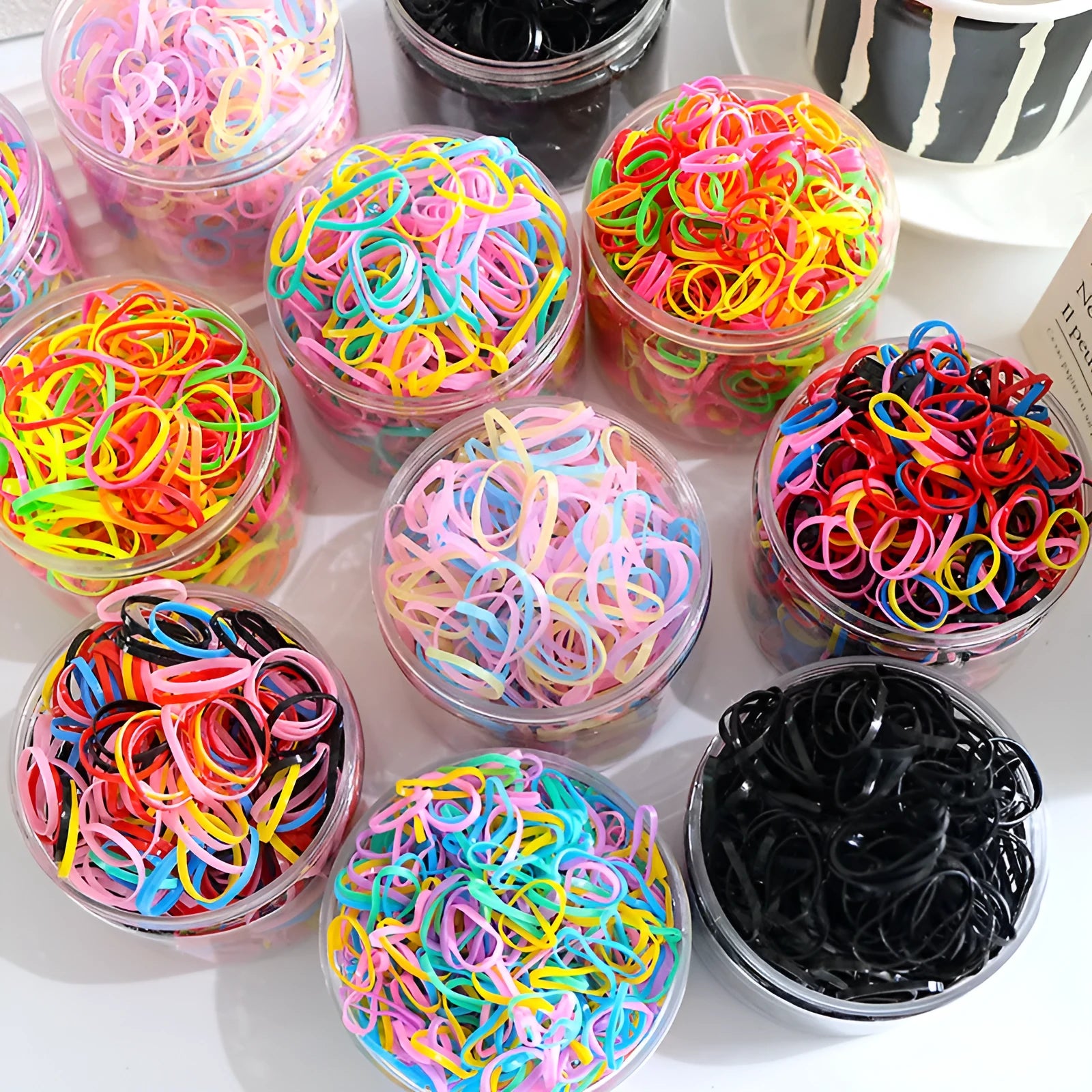 Multicoloured TPU baby hair ties in a reusable transparent storage container