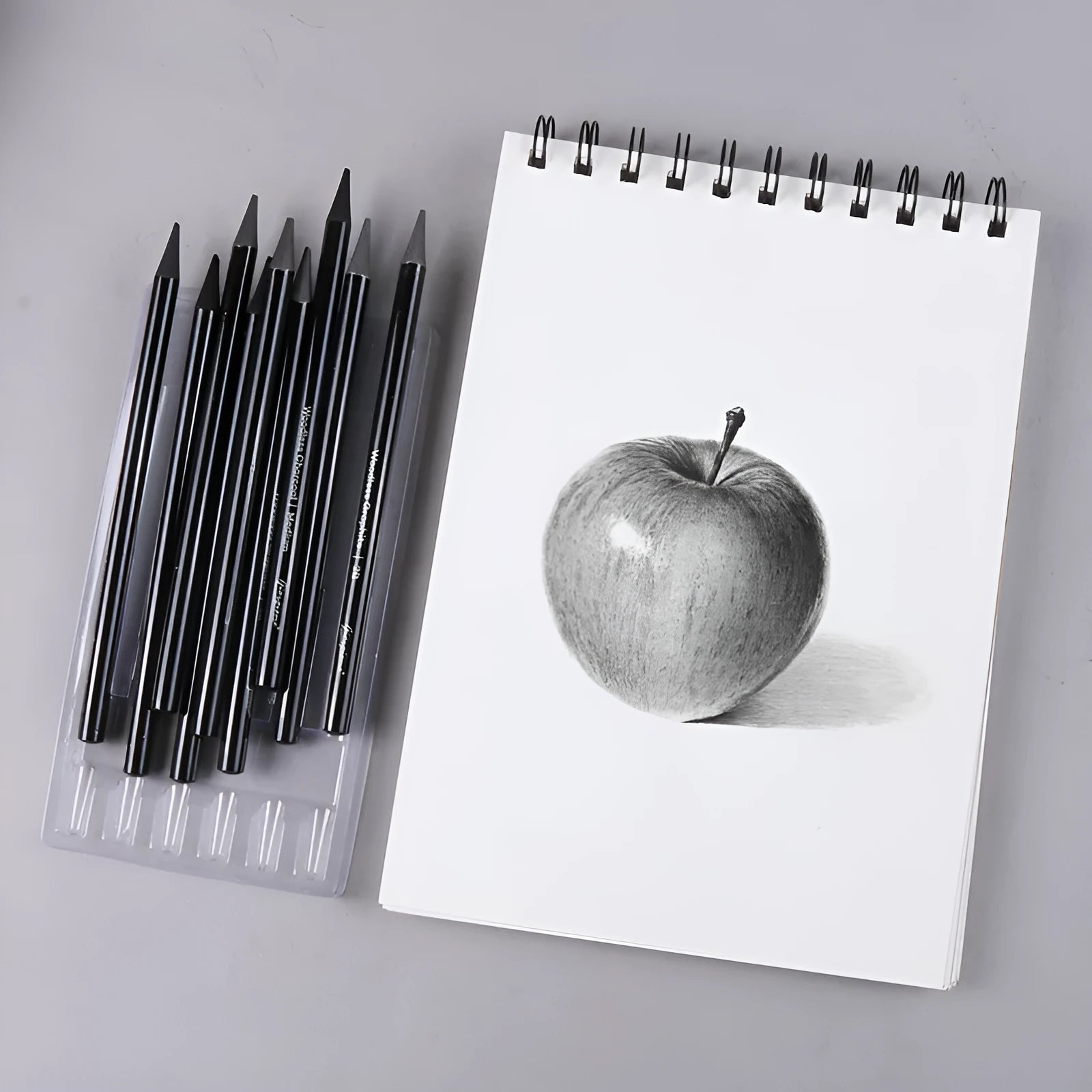 Set of six graphite and three carbonised drawing pencils with wooden casings on a white suction card.