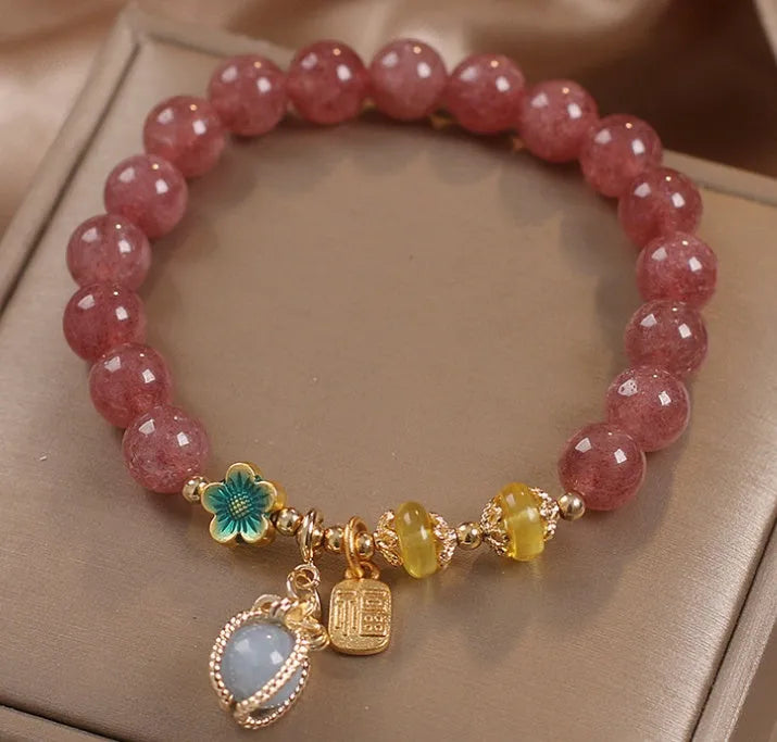 Red bracelet with strawberry quartz beads, alloy metal spacers, and rhinestone decorative details.