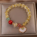 Close-up of a women's alloy bracelet with a yellow citrine jade ruyi pendant.