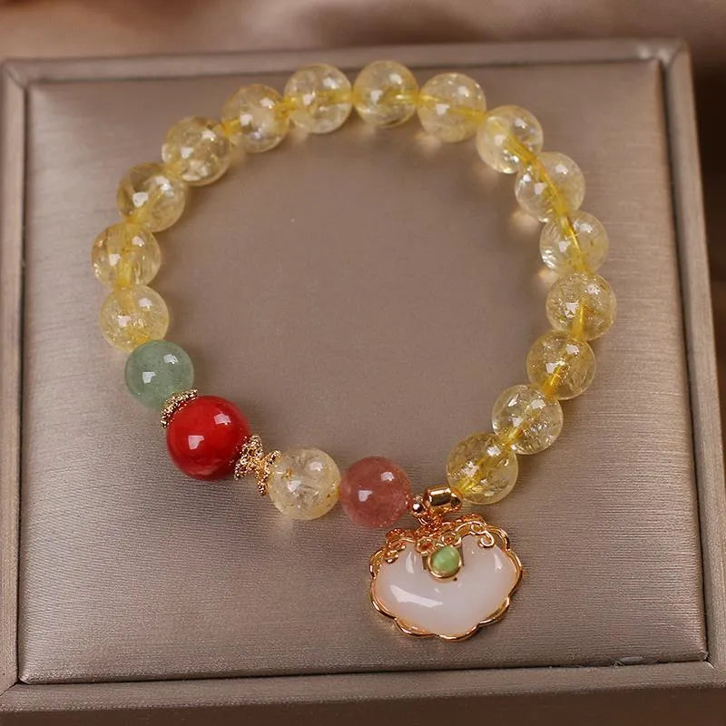 Close-up of a women's alloy bracelet with a yellow citrine jade ruyi pendant.