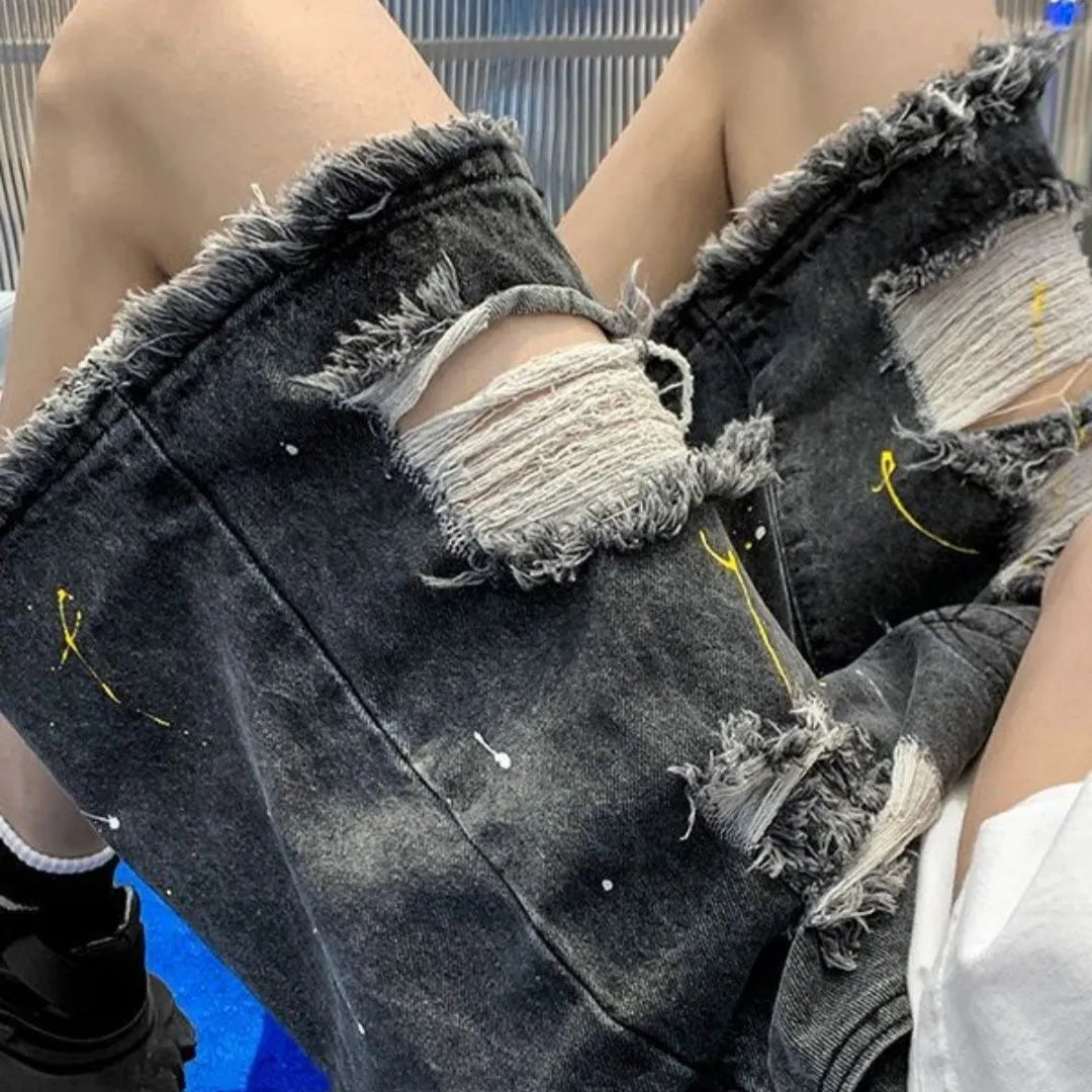 Man wearing loose light blue denim shorts with a distressed hole detail and water-washed finish.