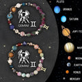 Set of twelve natural stone beaded bracelets with zodiac sign charms on a table.