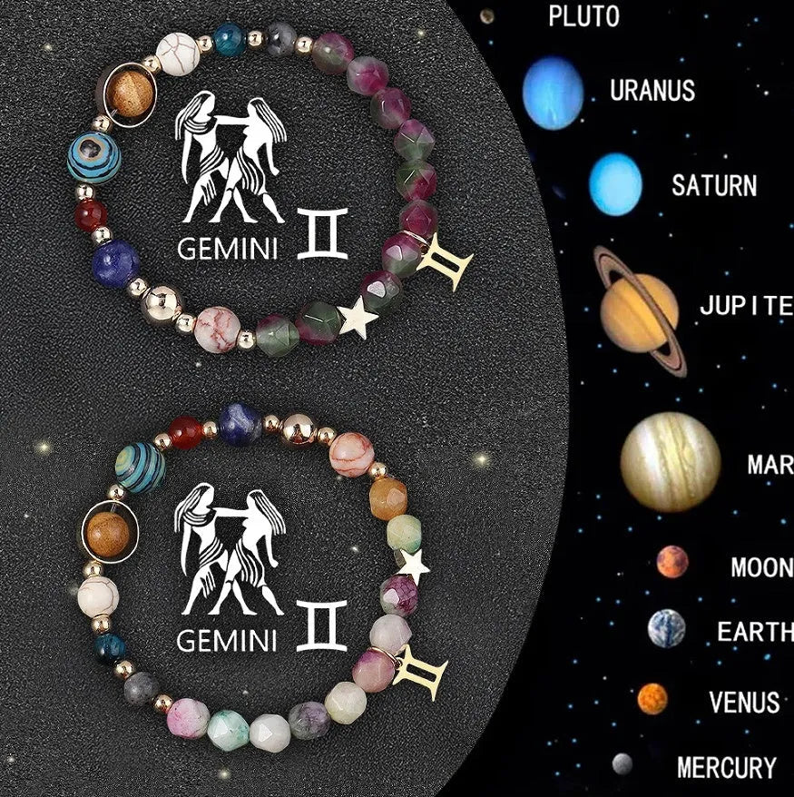 Set of twelve natural stone beaded bracelets with zodiac sign charms on a table.