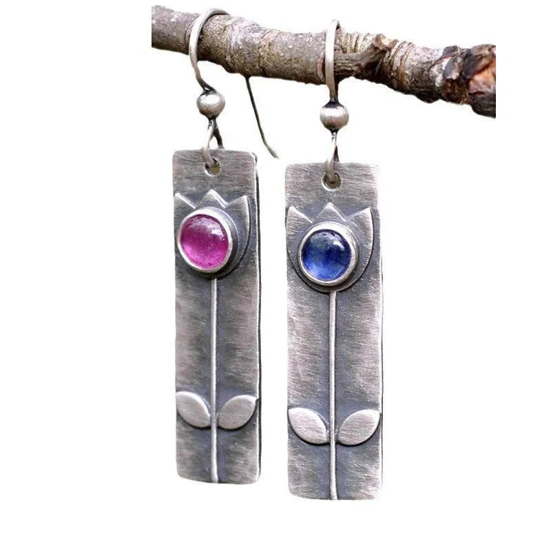 A pair of women's geometric earrings with an antique red finish and elliptical design details.