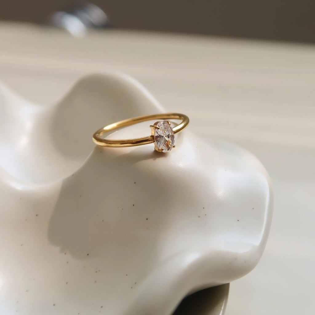 Golden love heart and oval stainless steel ring for women on a white background.