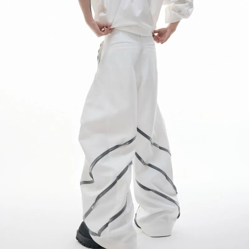 Men's black trousers with a deconstructing three-dimensional cut and pleats secured with metal striped rivets.
