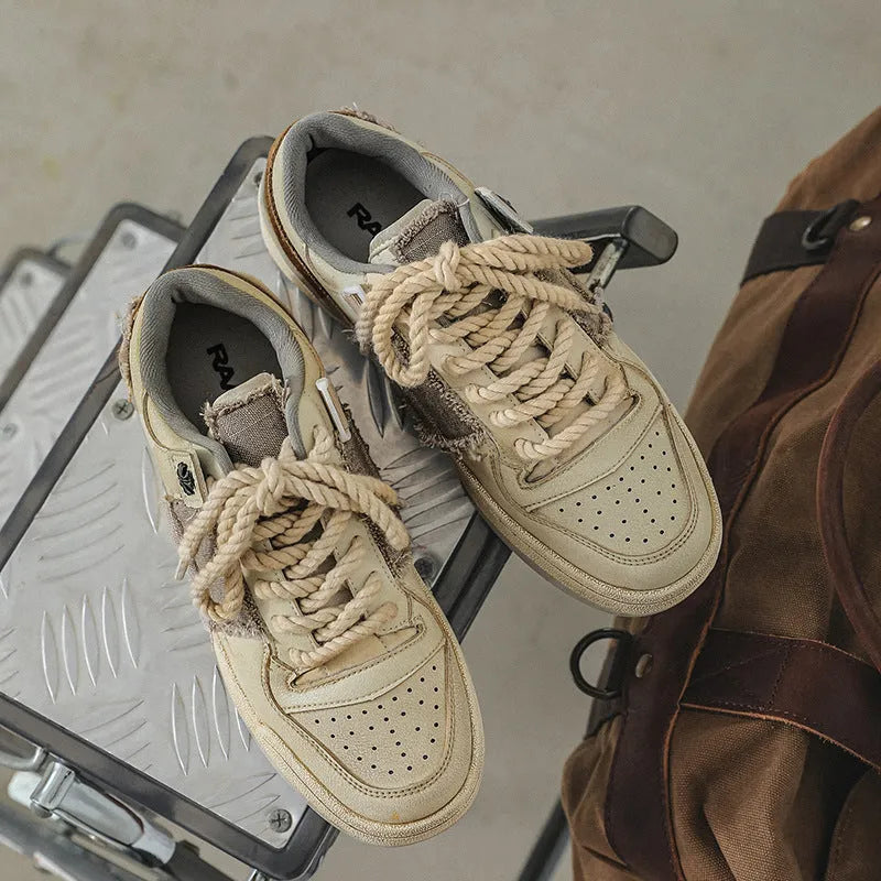 Beige vintage style low top skateboard shoes with flat rubber sole and lace-up front.