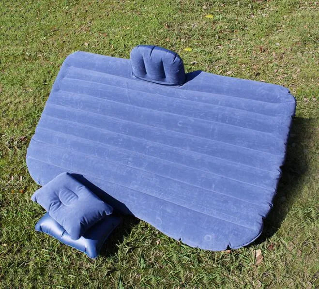 Black inflatable car bed with flocked surface and pillows set up in a car's back seats