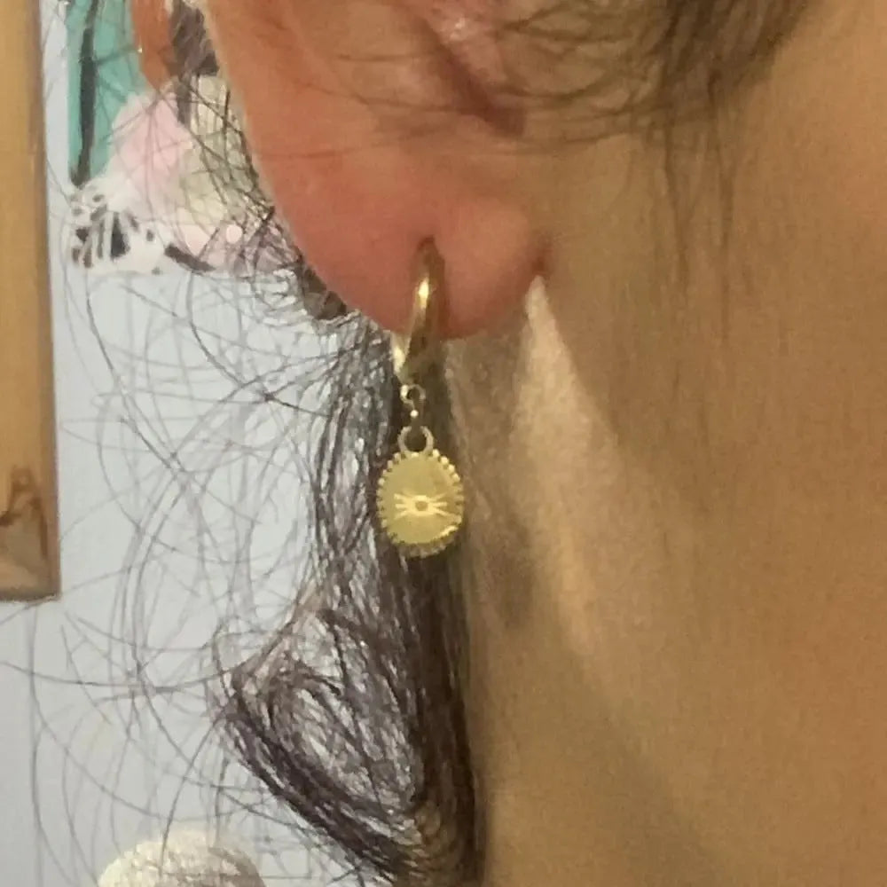 A pair of stainless steel ellipse-shaped button earrings for women on a plain background.
