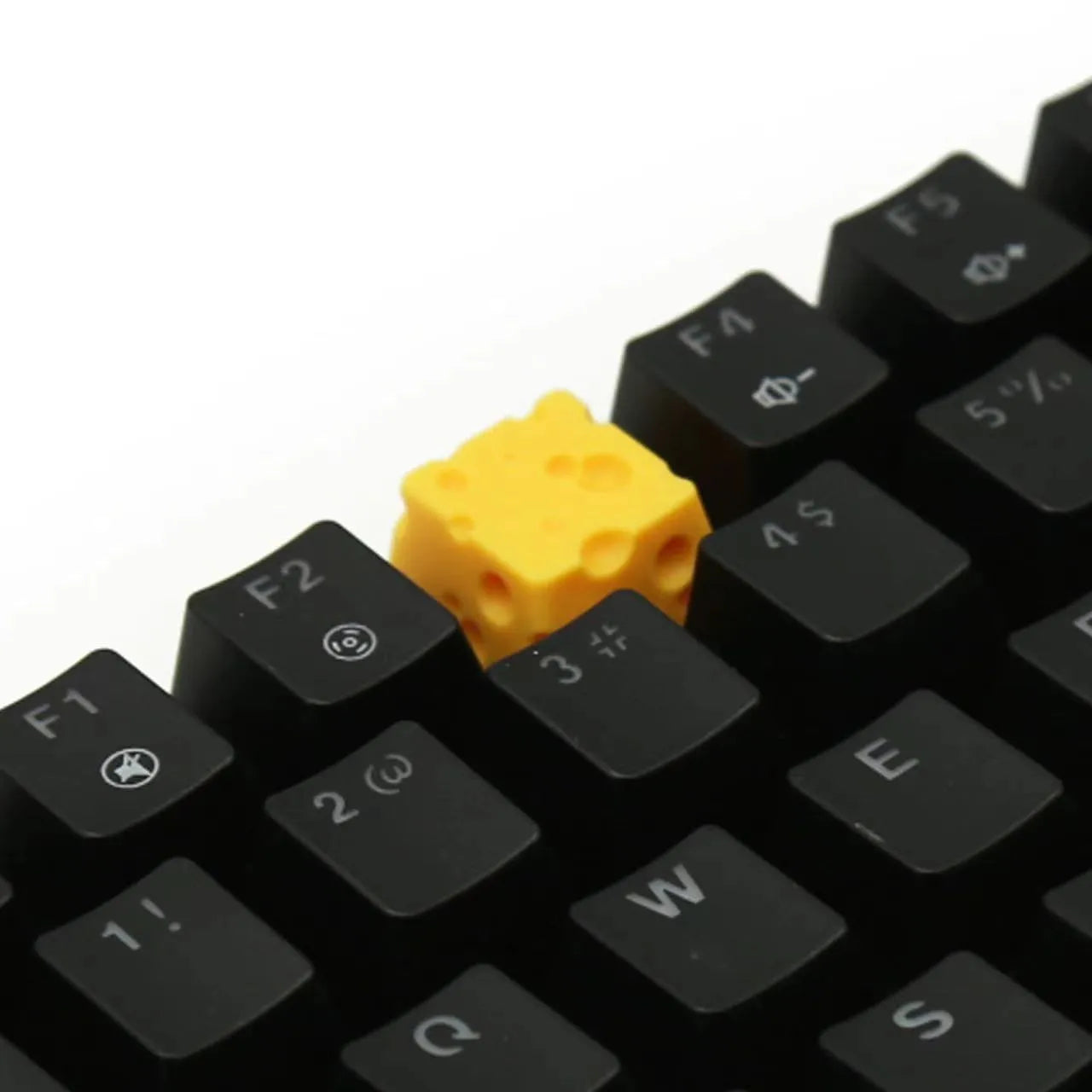 Close-up of a yellow resin cheese-shaped keycap for a mechanical keyboard.