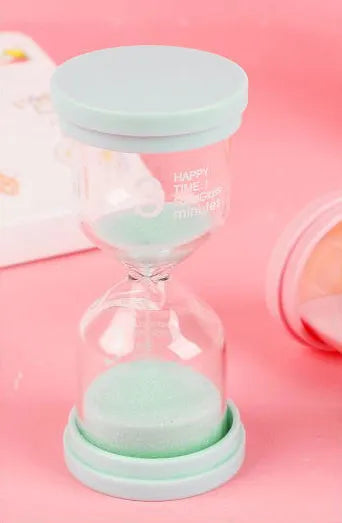 Handmade glass sand timer with blue sand, showing modern simplicity style on a desk.