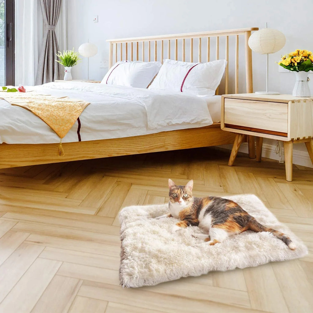 Grey fluffy pet sleeping pad for cats and dogs on a sofa, showing non-slip black bottom.