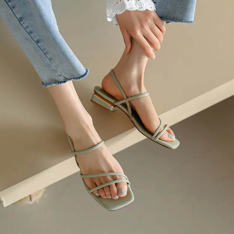 Women's beige flat strap Roman sandals with square open toe on a neutral background