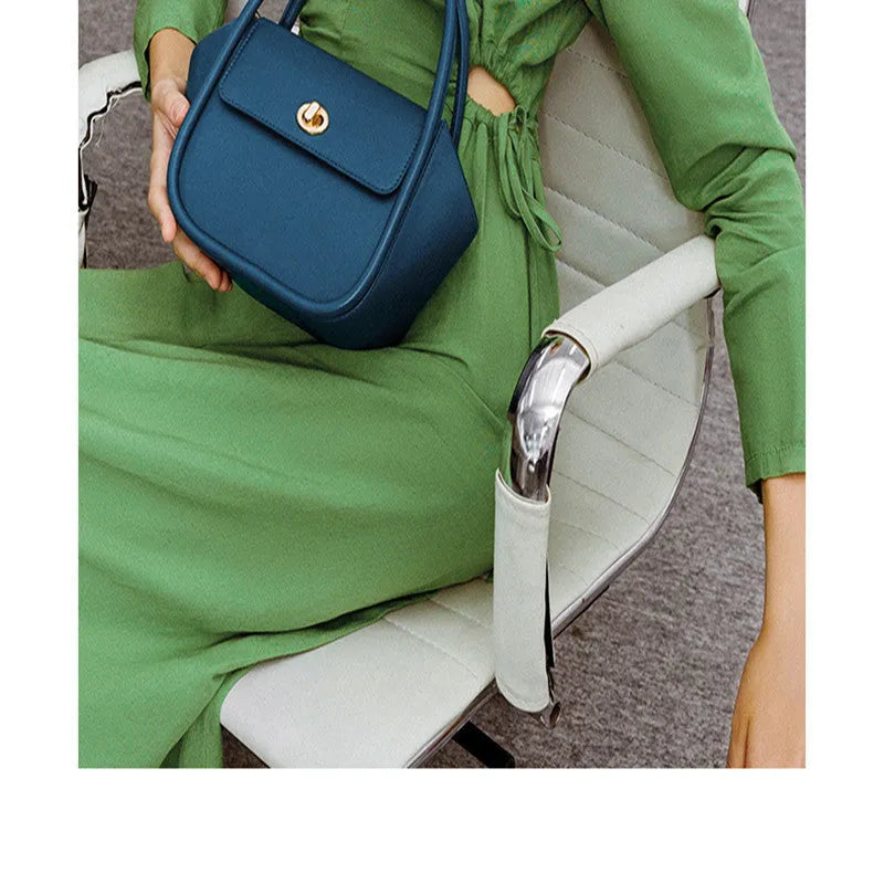A women's cow leather wing-shaped handbag with a latch closure and a single shoulder strap.
