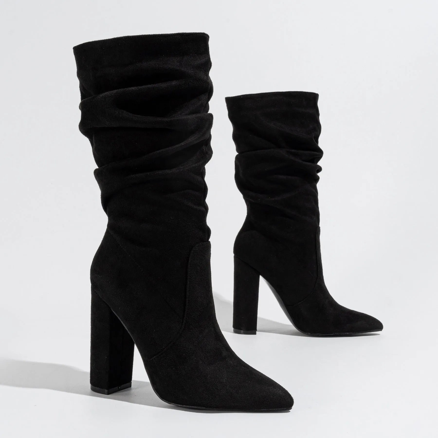 Black suede women's ankle boots with a chunky high heel and pointed toe on a neutral background.