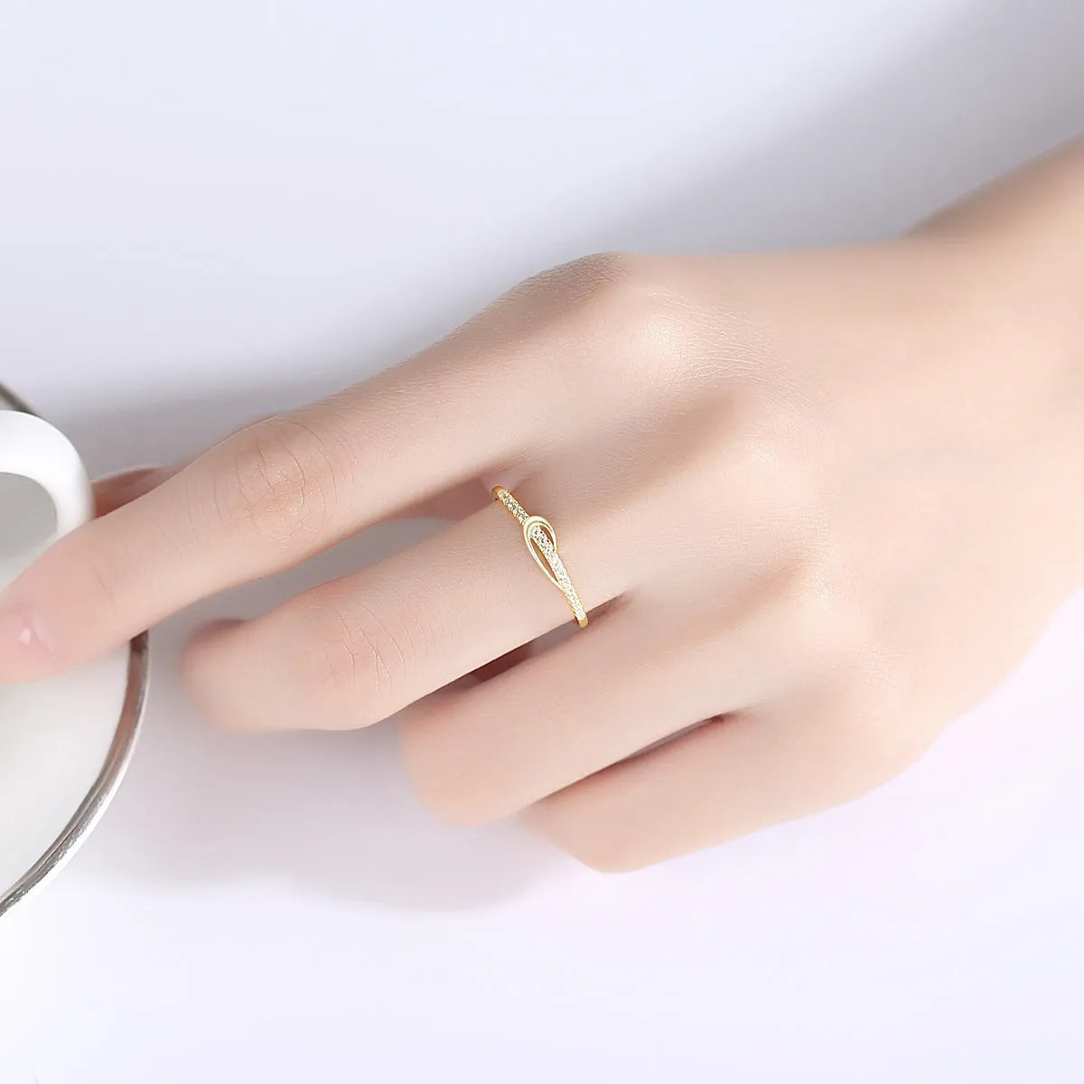 S925 silver bow ring with single row of diamond stones on a plain background