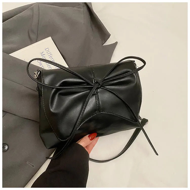 Women's black underarm crossbody bag with horizontal square shape and visible sewing details