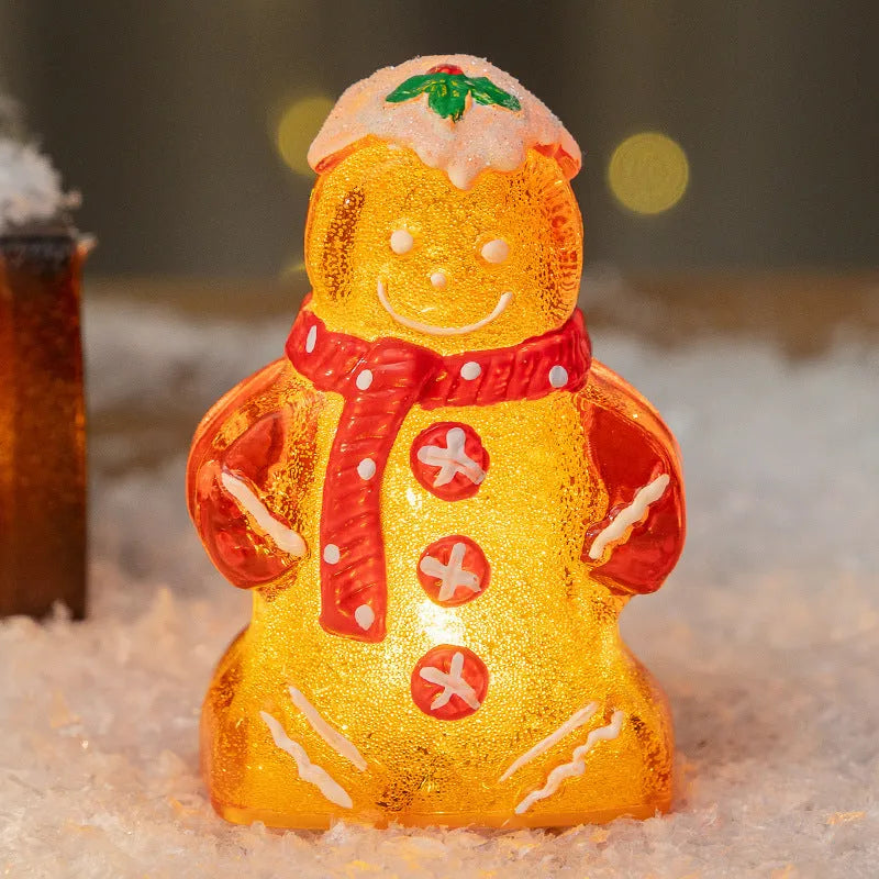 Glowing LED gingerbread man and snowman Christmas ornaments with coloured scarves on a festive tree branch.