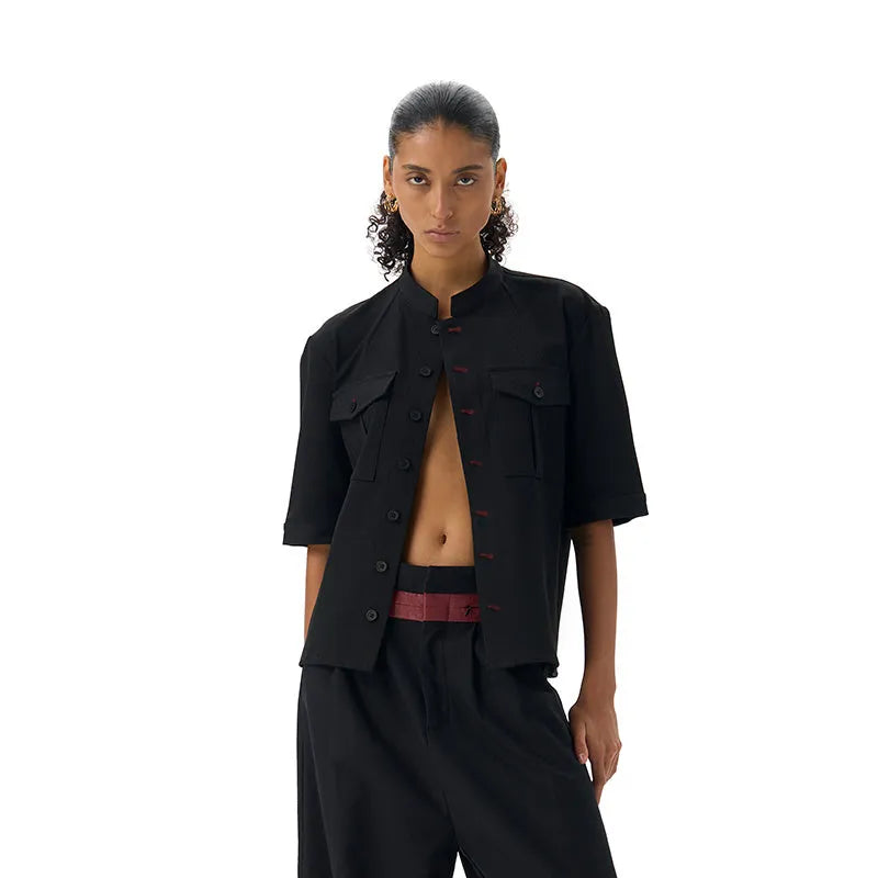 A black handmade half sleeve shirt with a shirt collar, shown on a hanger.
