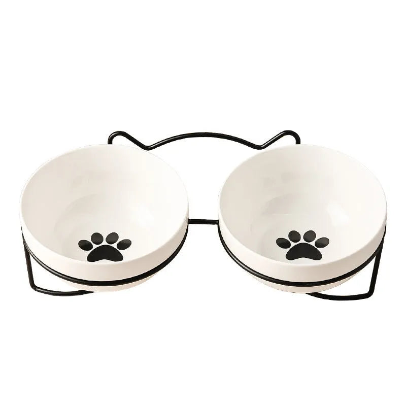 White ceramic cat bowl with paw print design in a black iron cat-ear frame.