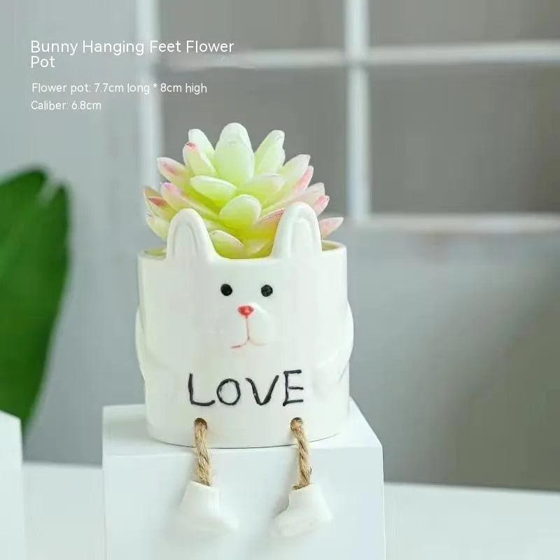 Ceramic hanging foot flowerpot in a cartoon style, shown on a desktop with a small succulent plant.