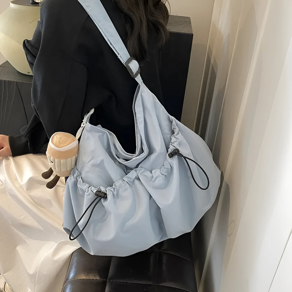 Green pleated polyester crossbody bag showing split pocket design and foldable construction