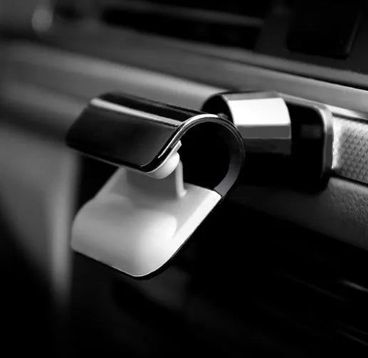Black universal car phone holder with 360-degree rotation on a car dashboard.