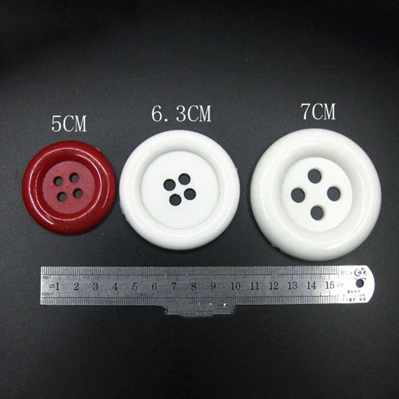 Assorted oversized round plastic buttons in black, white, red, blue and yellow on a white background.