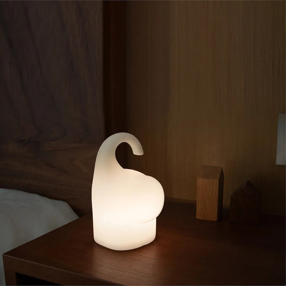 DOMI Elephant shaped silicone night light with warm white LED glow on a bedside table.