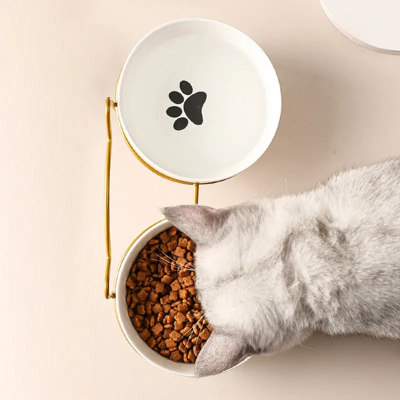 White ceramic cat bowl with cat footprints design on a black iron stand with cat-ear decoration.