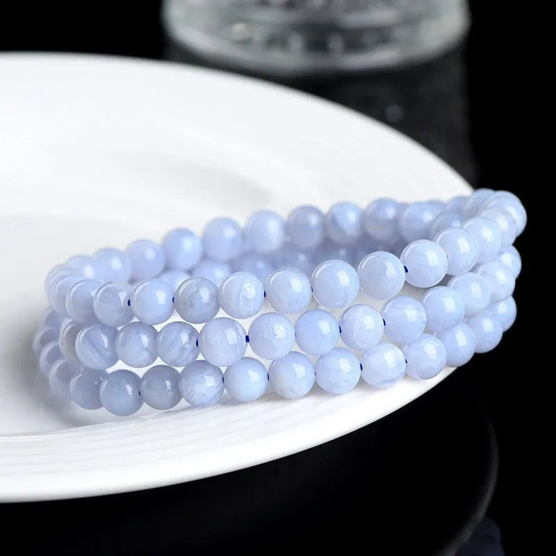Close-up of a blue agate bracelet with scattered beads and striped spheres on a wrist.