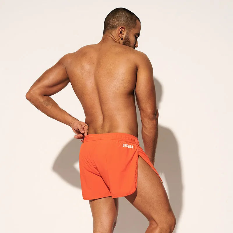 Men's loose elastic polyester shorts in orange, fluorescent green, and black colours for beach surfing.