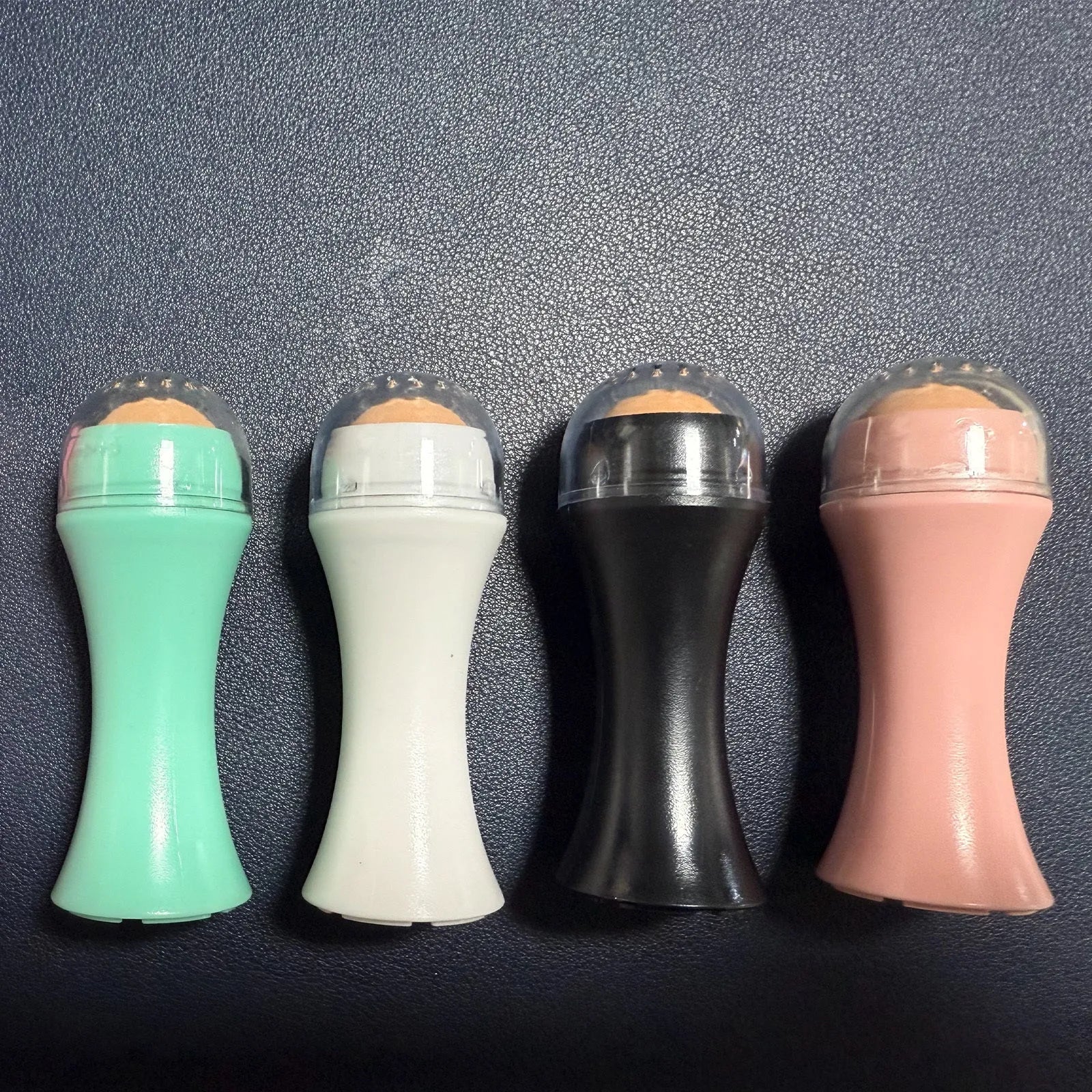 Volcanic stone oil-absorbing facial roller in pink on a white background
