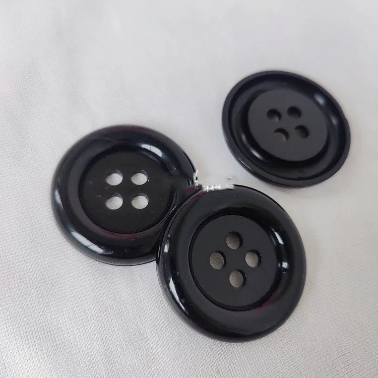 Assorted oversized round plastic buttons in black, white, red, blue and yellow on a white background.