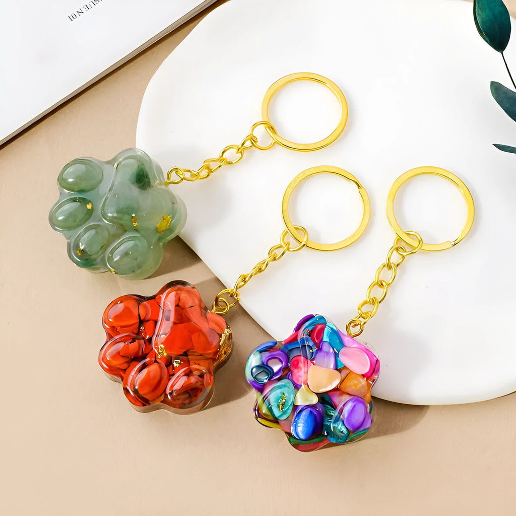 Small crystal cat's paw keychain pendant on a keyring, shown in various gemstone colour options.