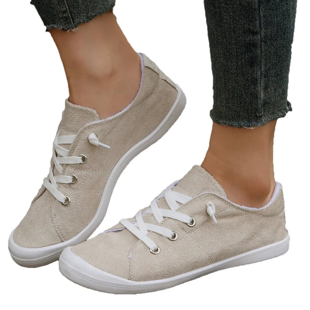 Women's creamy white low-top fabric casual sneakers with a rubber sole on a neutral background.