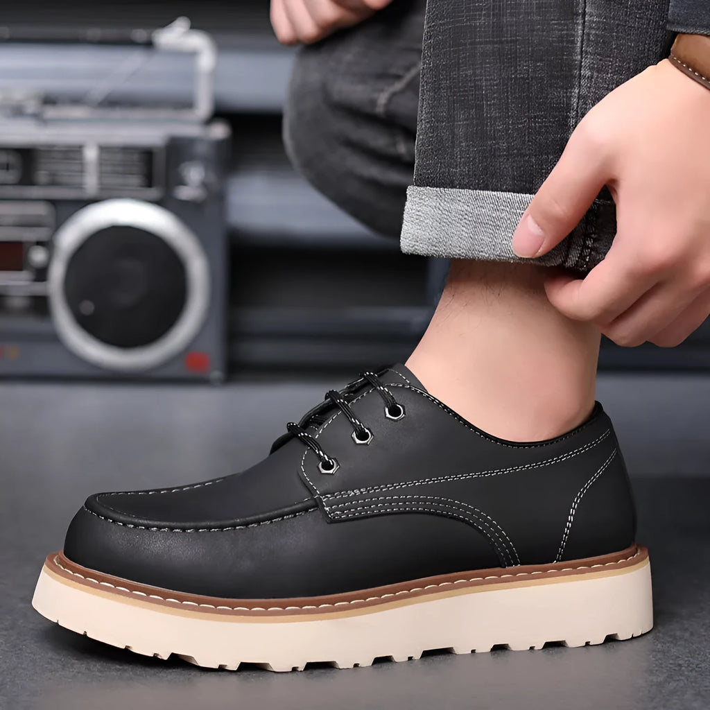 Men's black low-top Martin boots with round toe and rubber sole on a neutral background