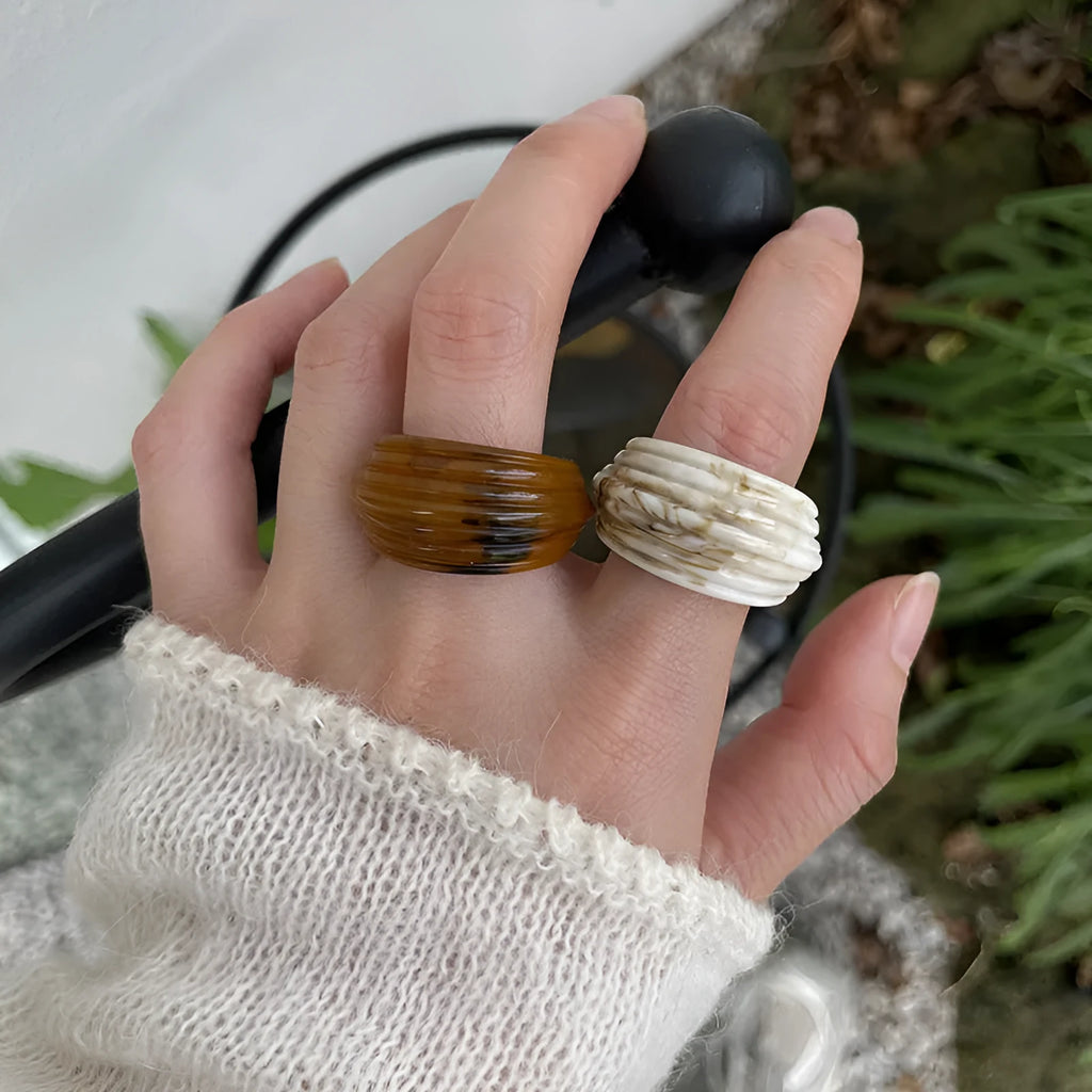Chinese style irregular geometric wide resin ring in brown or white on a plain background.