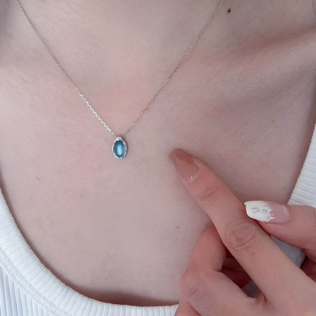 Navy blue water drop necklace with platinum accents on adjustable cross chain