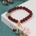Close-up of a retro-style women's cinnabar bracelet with purple gold sand colour, showing fu character design and tassels.