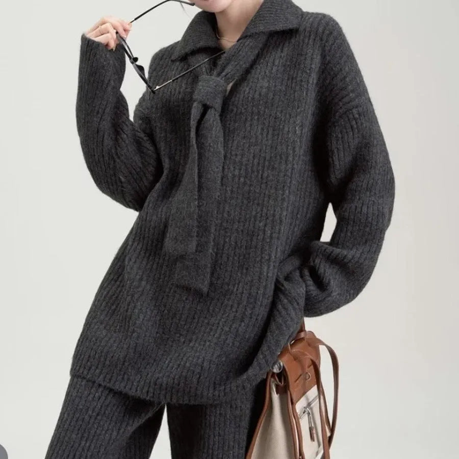 Women's beige knitted top and matching trousers from a two-piece acrylic sweater suit set laid flat.