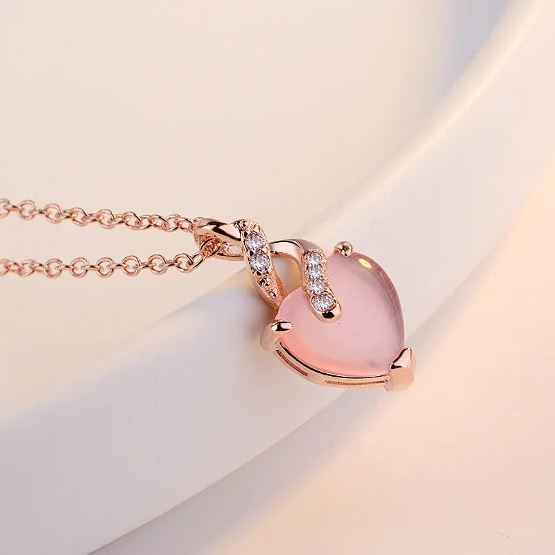 Rose gold women's necklace with heart-shaped pink crystal pendant on cross chain