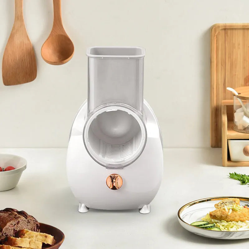 White electric vegetable slicer with suction base and multiple blades on a kitchen counter.