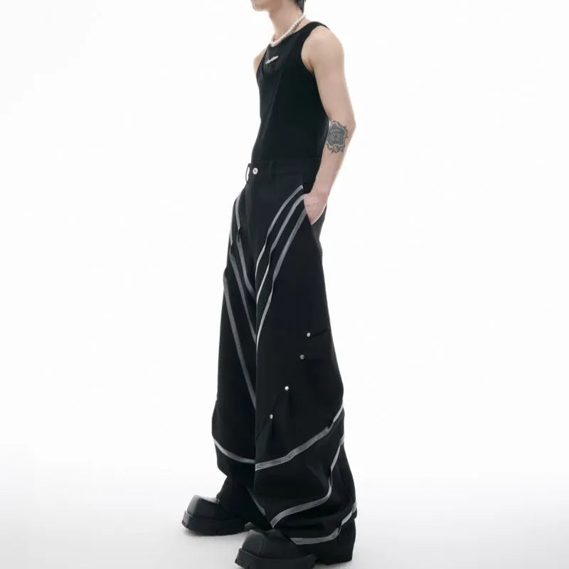 Men's black trousers with a deconstructing three-dimensional cut and pleats secured with metal striped rivets.