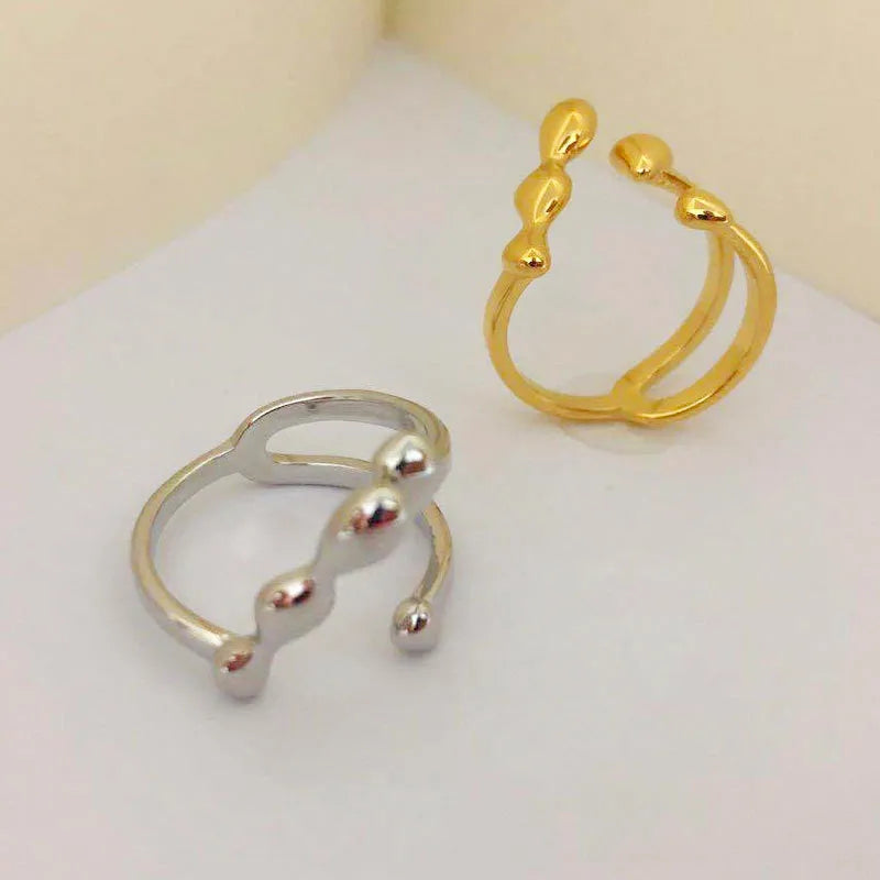 Gold tone brass opening ring with spherical circular design on a finger.