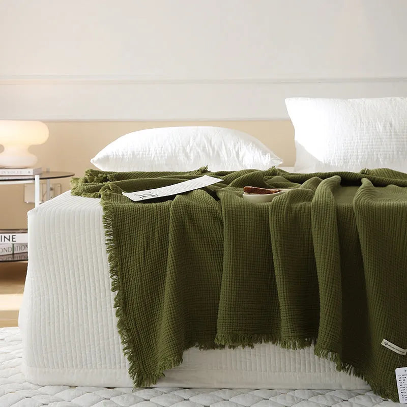 Four-layer gauze cotton blanket with tassel trim in navy blue colour, laid flat.